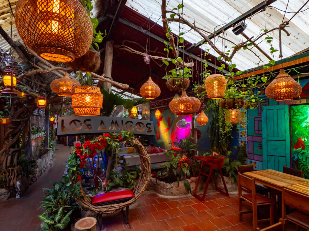Lanterns, plants, and colourful murals inside Los Amigos Hostel, one of the best places to stay in Flores, Guatemala.