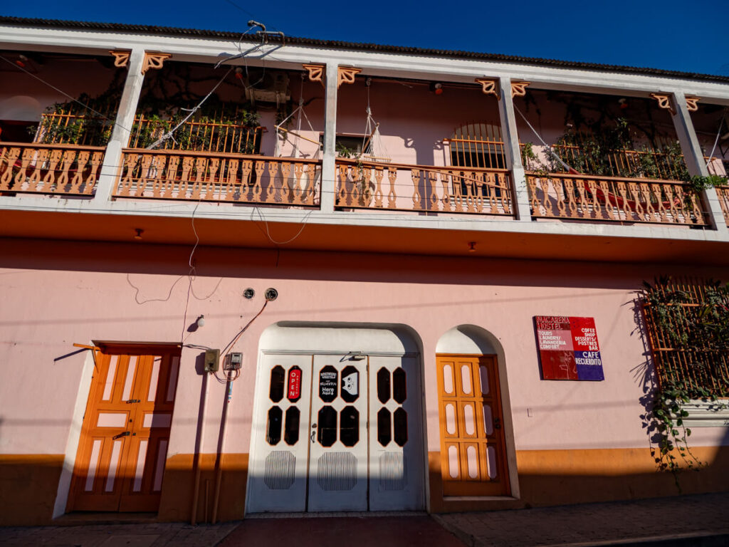 The faded pink exterior of Macarena Hostel, one of the best places to stay on a budget in Flores, Guatemala.