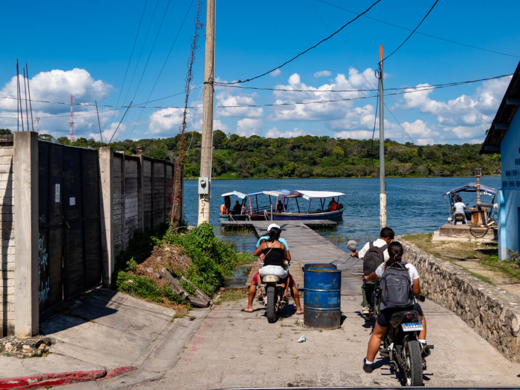 People on motorbikes waiting to board a small boat on Lake Peten Itza in Isla de Flores, Guatemala.