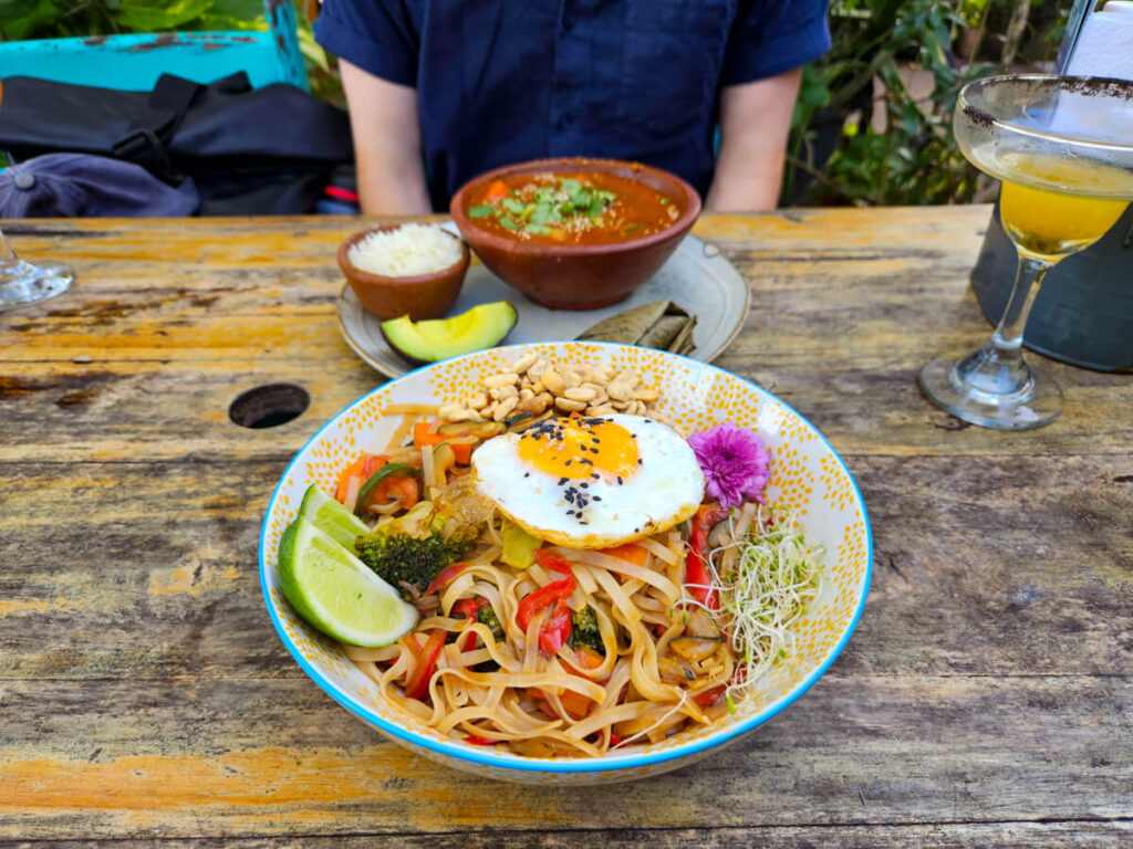 Bowls of pad Thai and pepian at a restaurant in Isla de Flores, Guatemala.