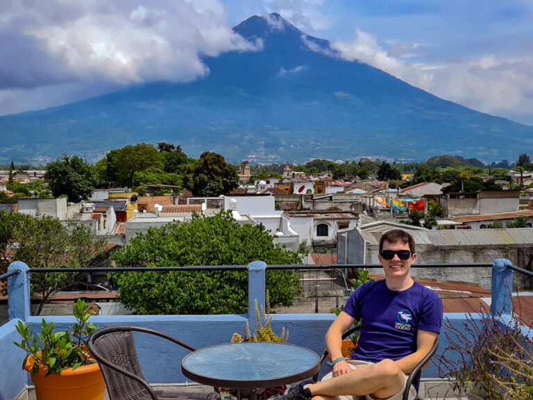 Dan sitting at a table on a rooftop terrace in front of the mighty Agua Volcano in Antigua, Guatemala.