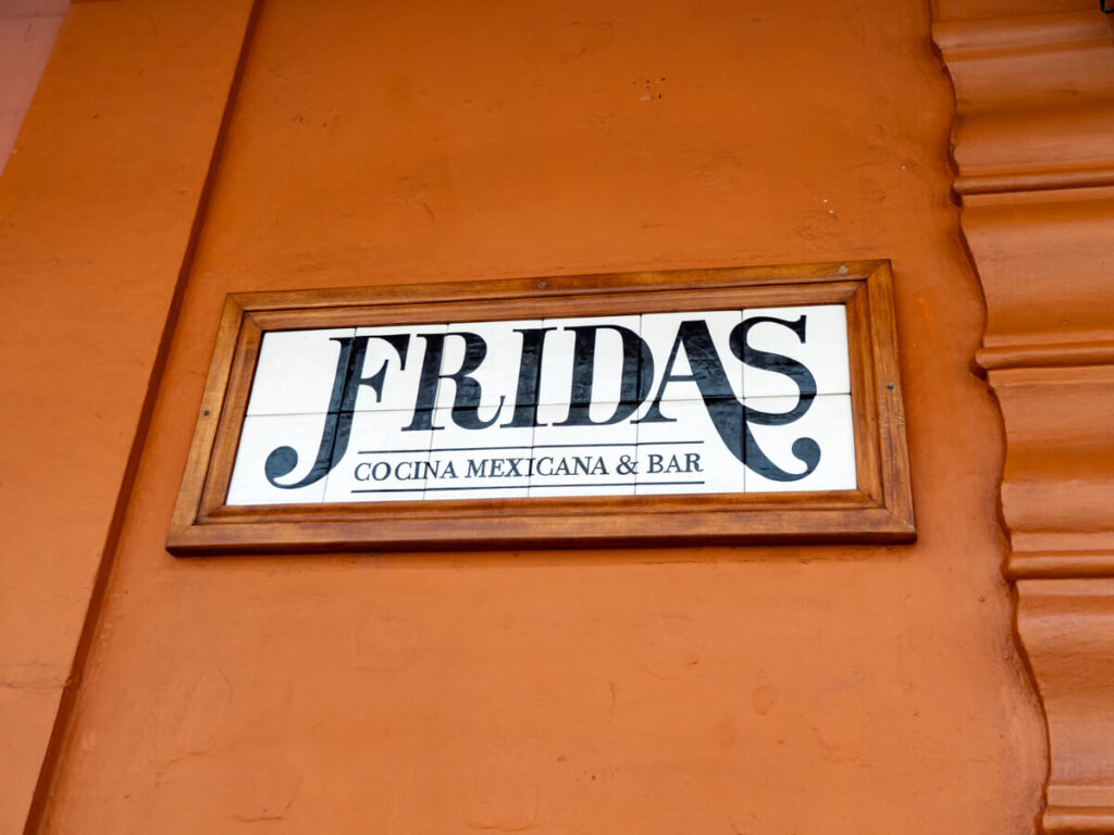 The brown wall of and sign for Frida's, one of the top restaurants in Antigua, Guatemala.