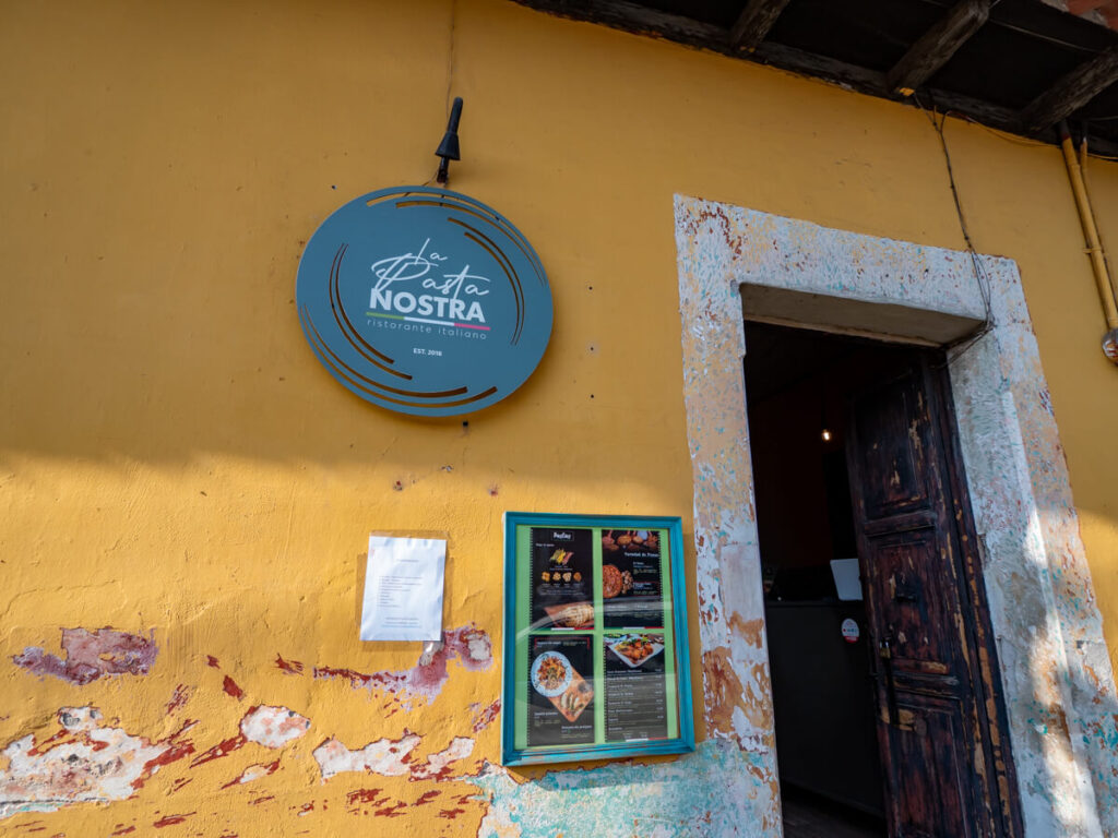The yellow façade of and sign for La Pasta Nostra, one of the best Italian restaurants in Antigua, Guatemala.