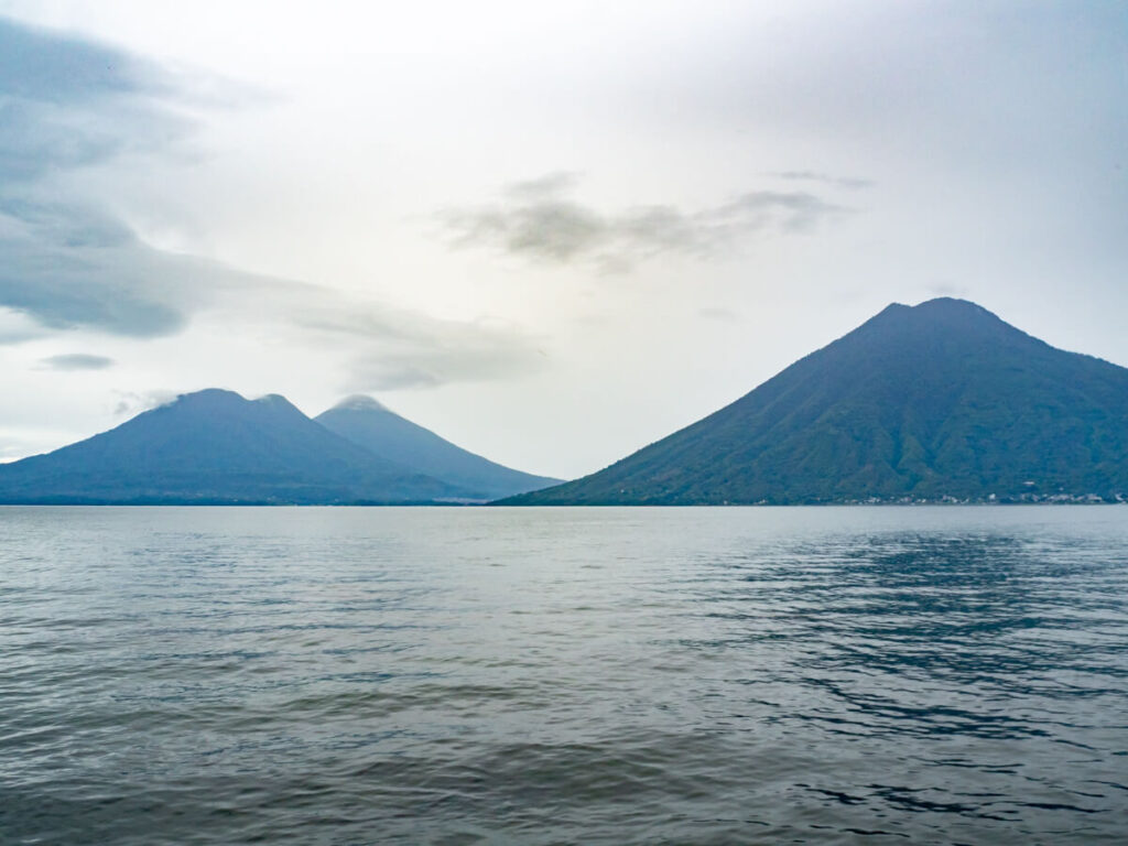The imposing volcanoes, San Pedro,  Atitlán, and Tolimán, across the still water of  Lake Atitlán, Guatemala.