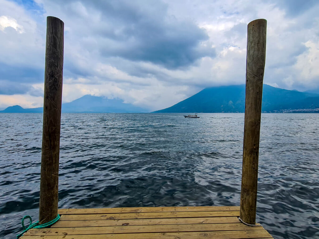 A small boat sailing on Lake Atitlán, viewed form a wooden dock.