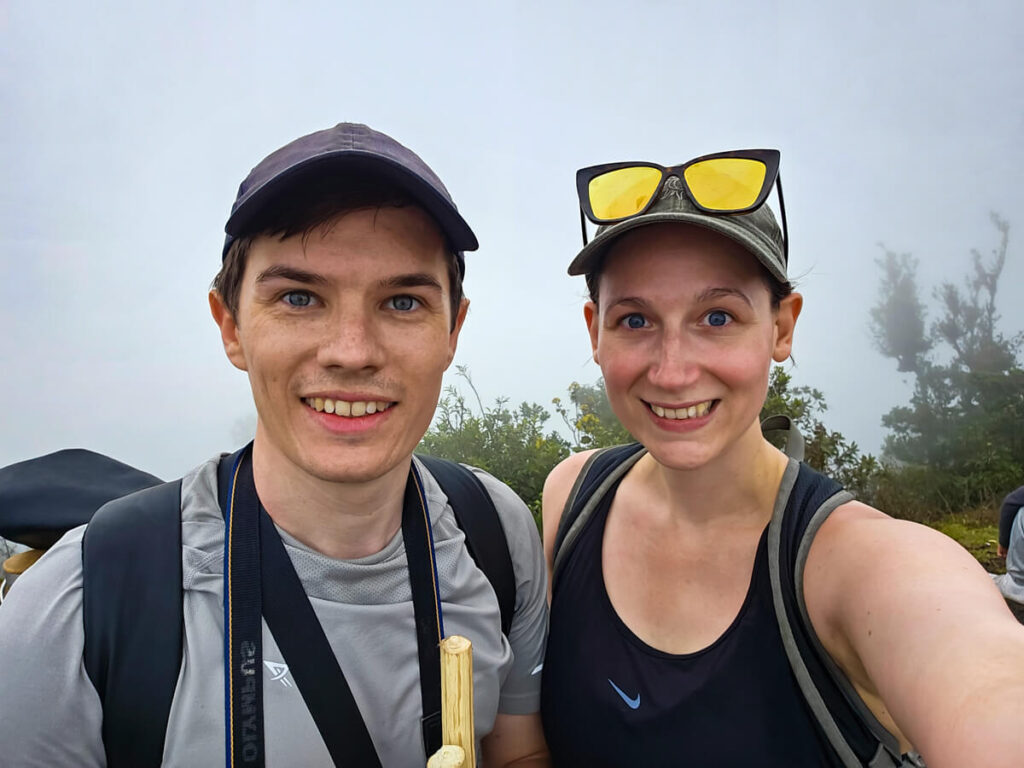 Dan and Lucy smiling at the camera on Pacaya Volcano, in front of thick fog.