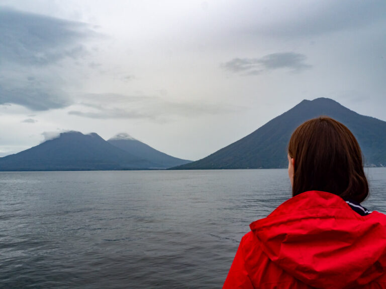 Lucy in a red coat looking out at the volcanoes on Lake Atitlán, Guatemala.