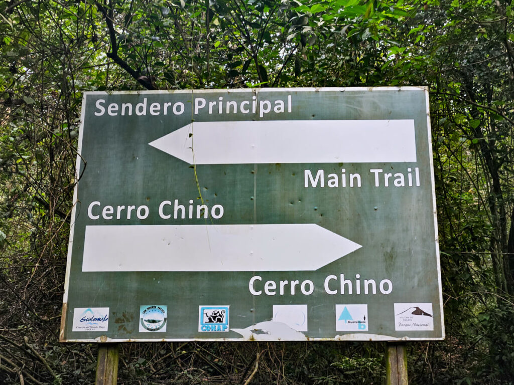 A sign pointing to trails on Pacaya Volcano, leading to the Sendero Principal (main trail) and Cerro Chino (viewpoint).