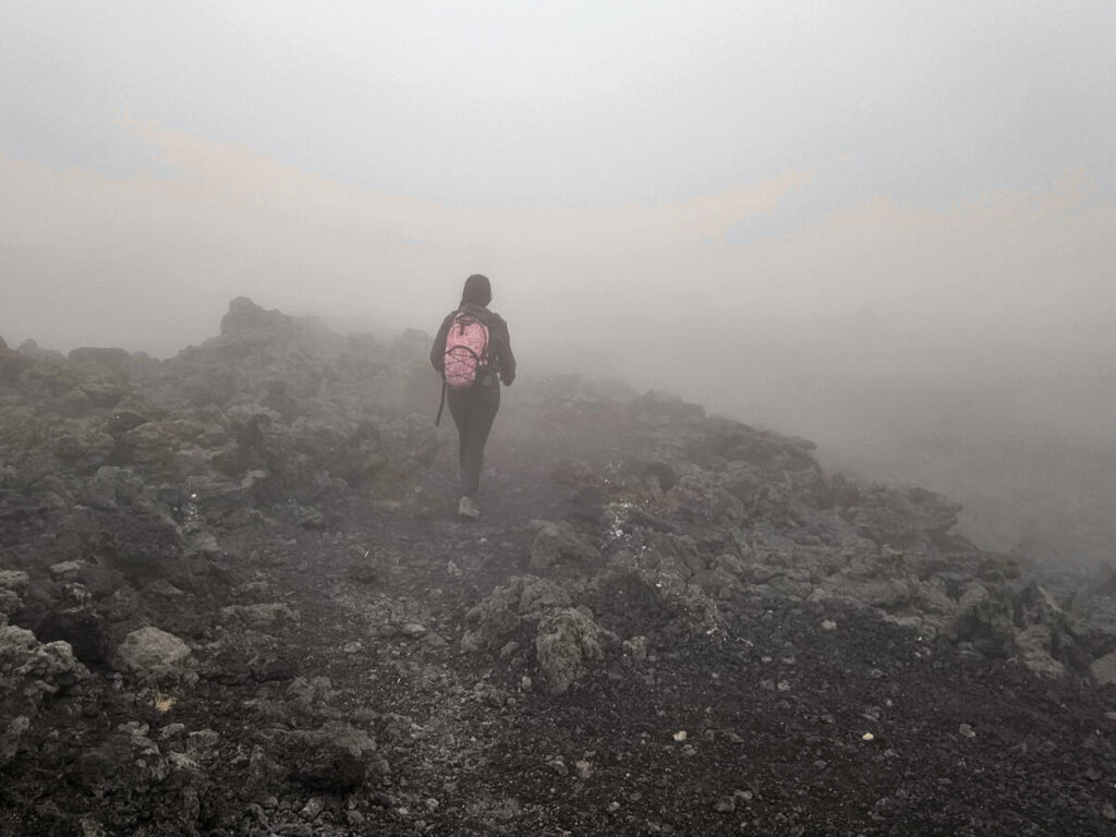 A guide disappearing into fog while leading a Pacaya Volcano tour.