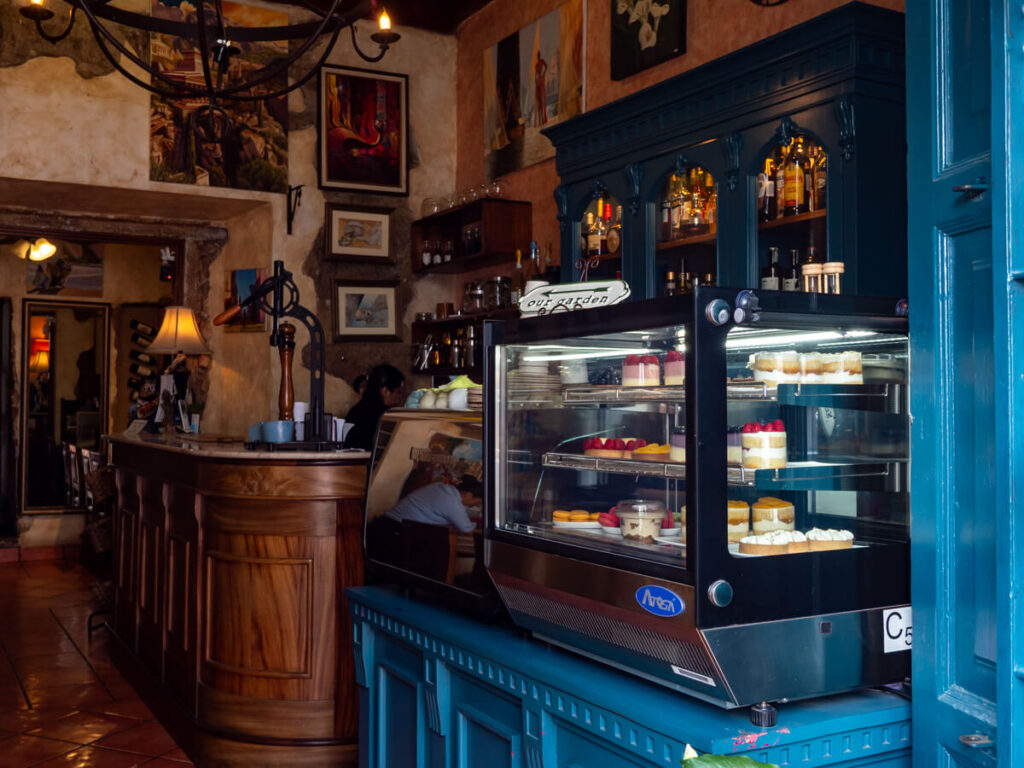 The warmly lit interior of Sobremesa in Antigua, Guatemala, with a large blue cabinet of desserts.