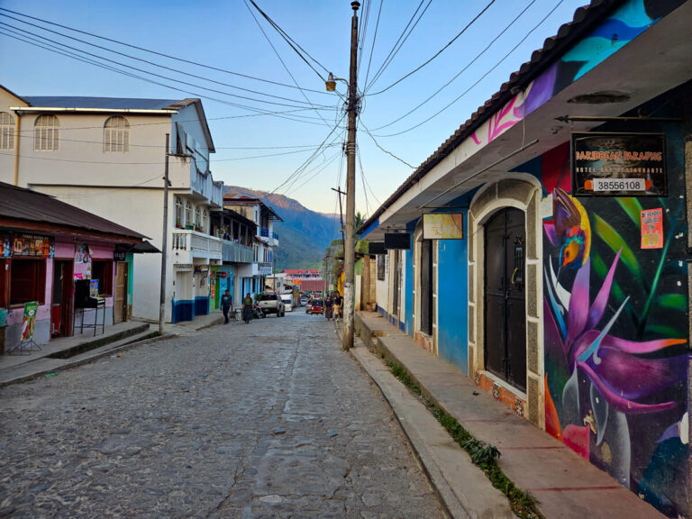 Colourful street art decorating buildings that line a cobbled street in the small town of San Agustín Lanquín, Guatemala.