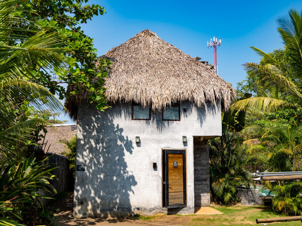 A white building with a thatched palapa roof in BarriOceano, a hotel in El Paredón.