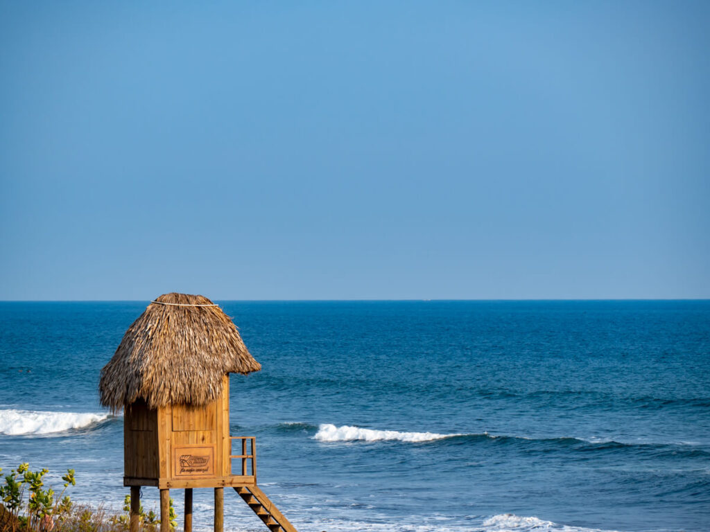 A wooden lifeguard hut overlooking the blue Pacific Ocean on the beach in El Paredón, Guatemala.