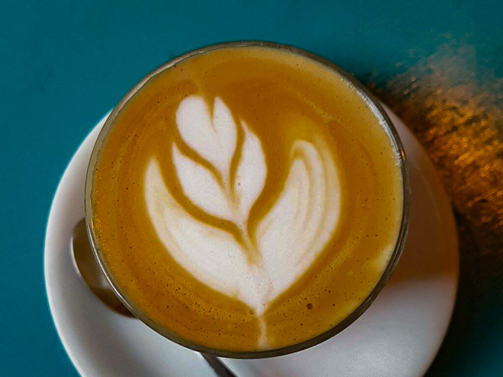 A warm cup of coffee with a leaf pattern carefully crafted on top.