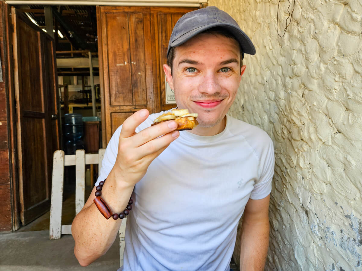Dan smiling with a piece of coconut bread in a café in Livingston.