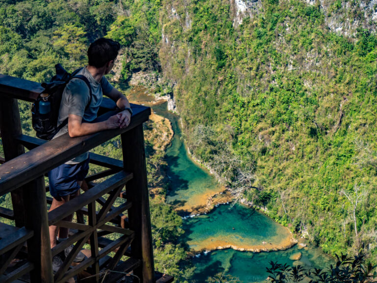 Dan looking out at the blue pools of Semuc Champey in Guatemala's jungle from the wooden observation deck at the mirador.