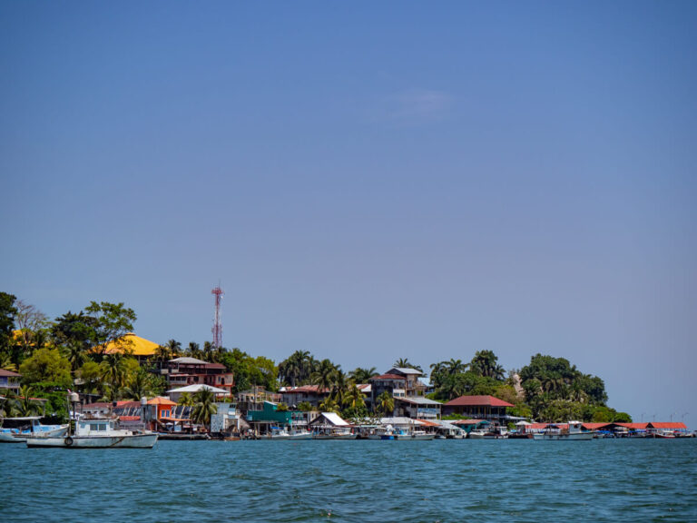Boats and riverside houses along the Río Dulce in Livingston, Guatemala.
