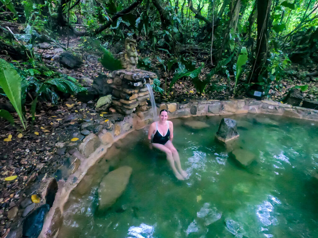 Lucy sitting under a waterfall in a geothermally heated pool in Luna Jaguar Spa, Honduras.