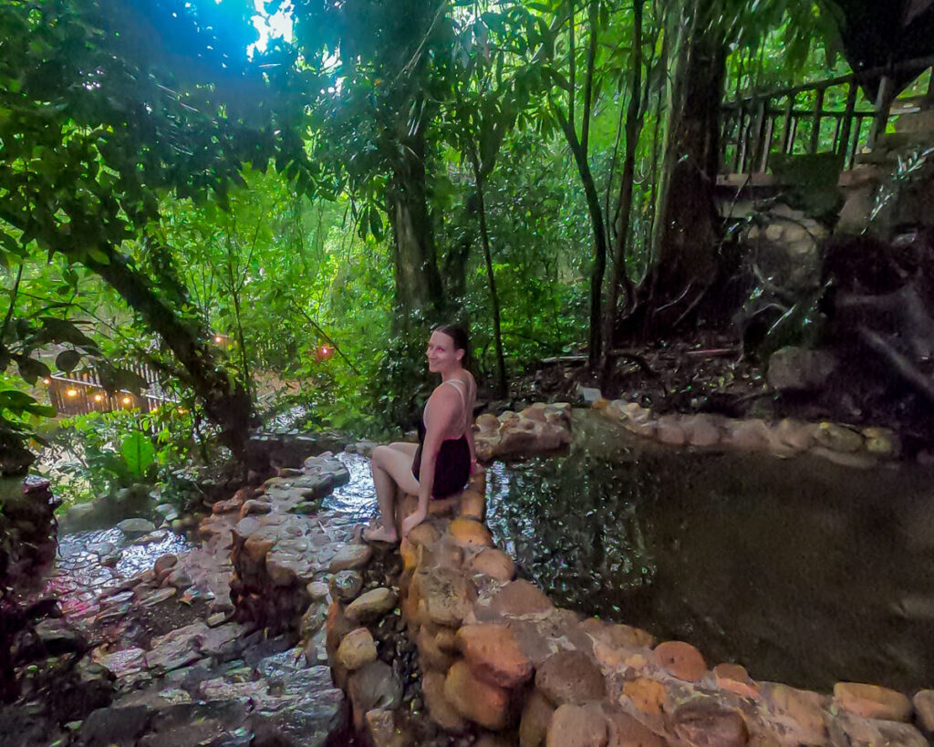 Lucy sitting on the edge of a natural hot spring pool in Luna Jaguar Spa, Copán Ruinas.