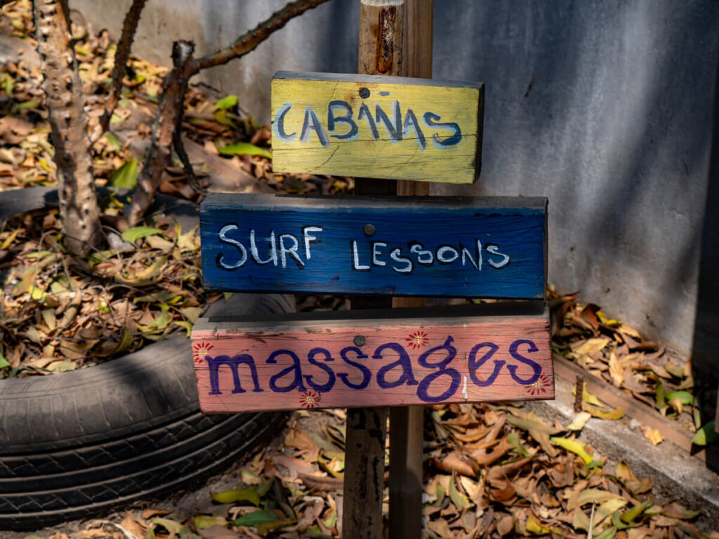 A sign outside Macarena Hotel in El Paredón advertising cabanas, surf lessons, and massages.