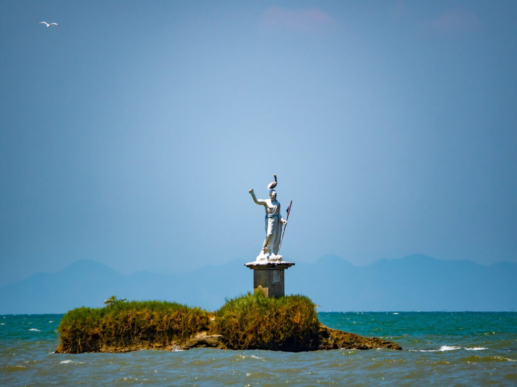 A pelican on a statue of El Salvador del Mundo in the sea in Livingston, Guatemala.
