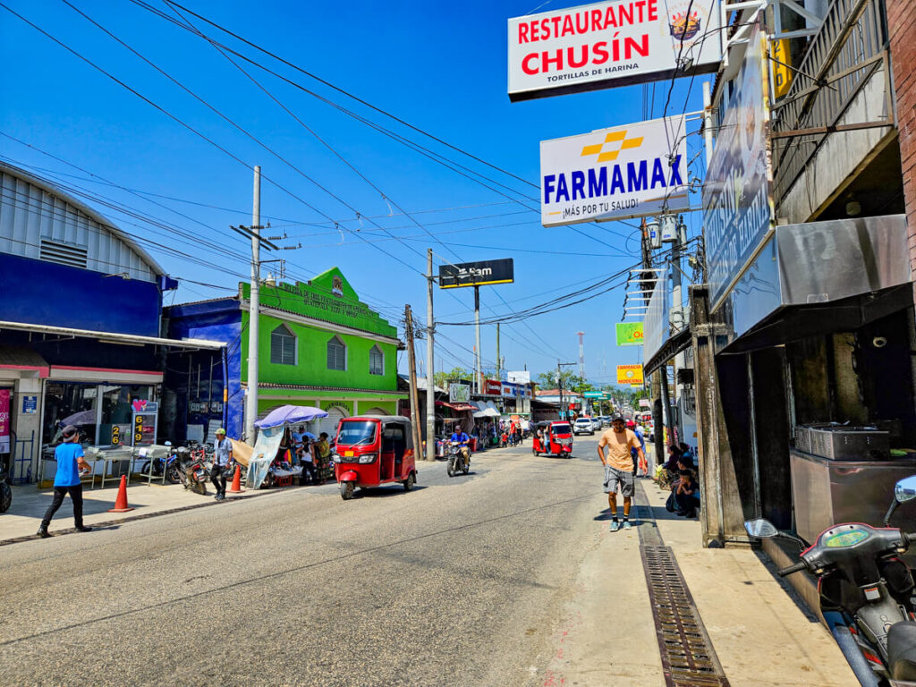 A tuk-tuk driving along the main road in Río Dulce town.