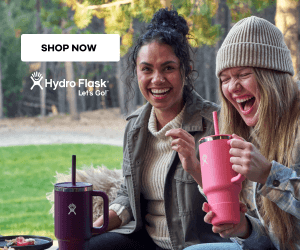 Two women laughing while holding HydroFlask water bottles.