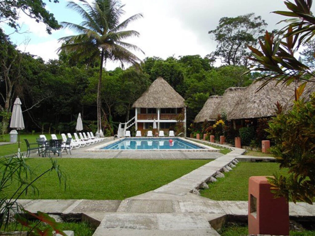 A grassy outdoor space with a pool in Hotel Tikal Inn.