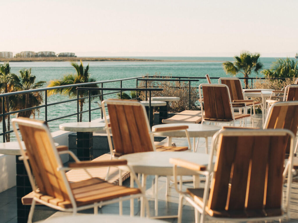 Chairs and tables in a rooftop restaurant in Baja Club Hotel looking out over La Paz and the sea.