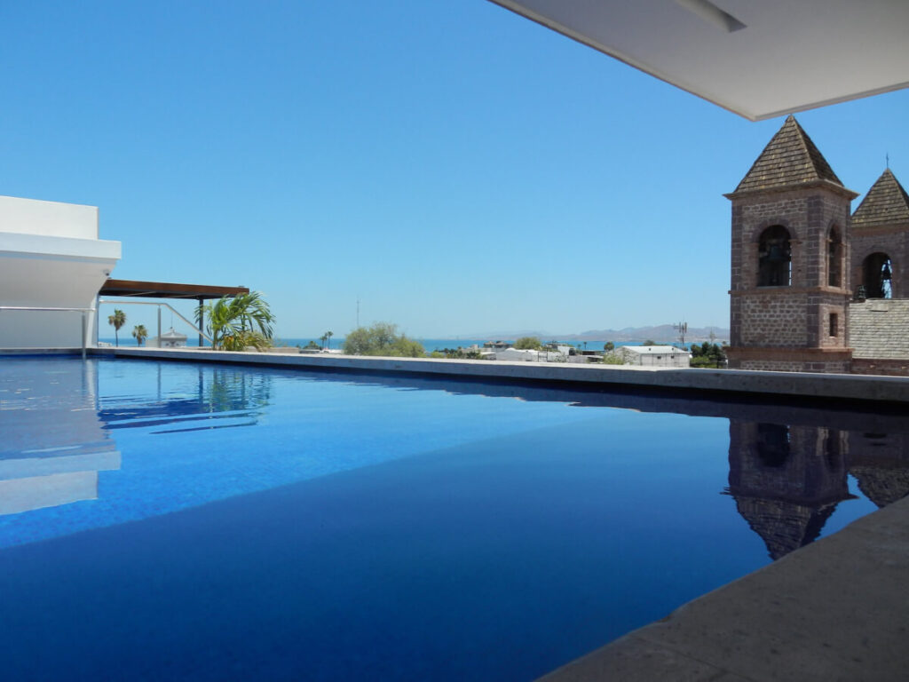 A still hotel pool overlooking the dusty pink cathedral in La Paz, Mexico.
