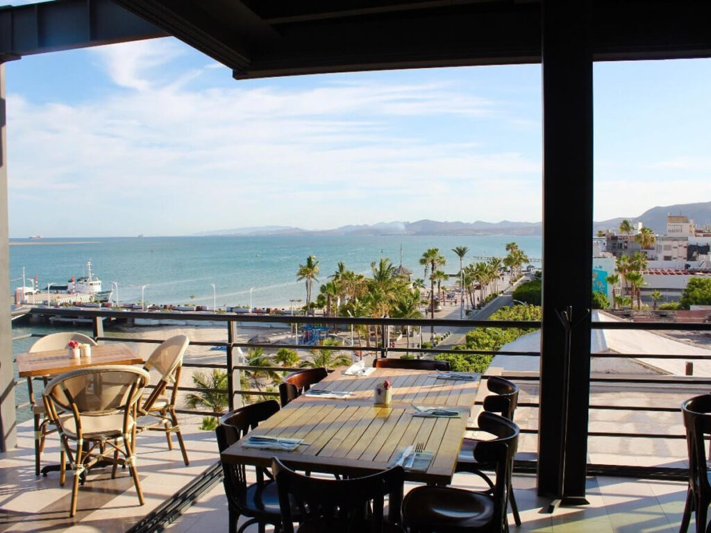 A shaded veranda in the Seven Crown Hotel looking out over La Paz malecón and the sea.