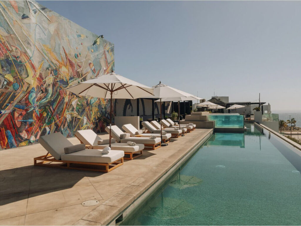 Loungers by a pool with sea views at Hotel El Ganzo in San Jose del Cabo.