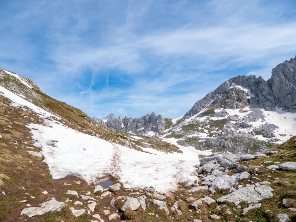 Footprints leading over a snowbank towards the distant limestone peaks of the Zupci mountains along the Bobotov Kuk trail.