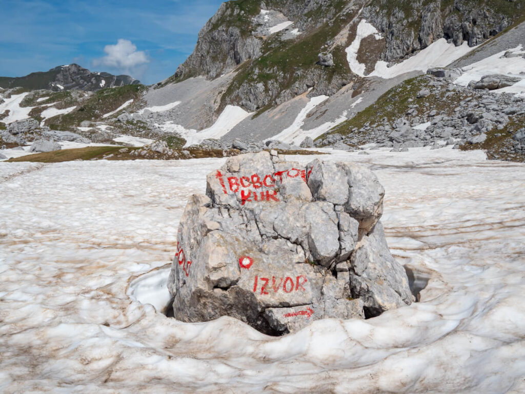A boulder with red paint indicating the way to Bobotov Kuk and Izvor.