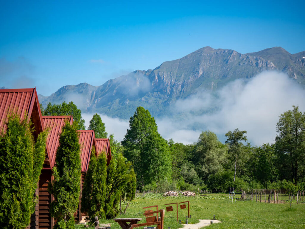 Mist rolling across the mountains behind a row of wooden cabins in Eko Katun Rosi.