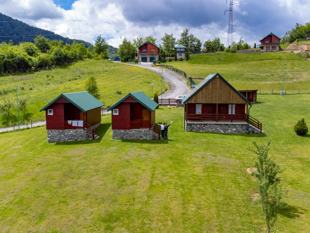 A trio of wooden Cabins set on a grassy hillside at Eco Village Coric, near Biogradska Gora National Park.