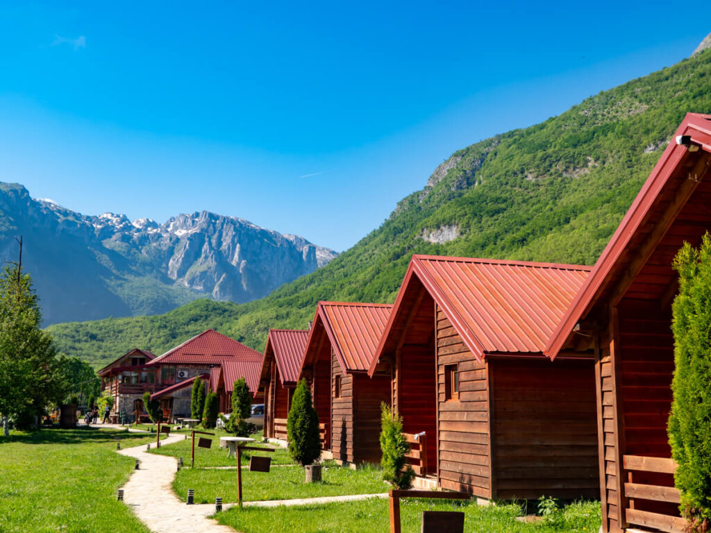 Wooden cabins in a row beneath the mountains of the Ropojana Valley in Prokletije National Park.