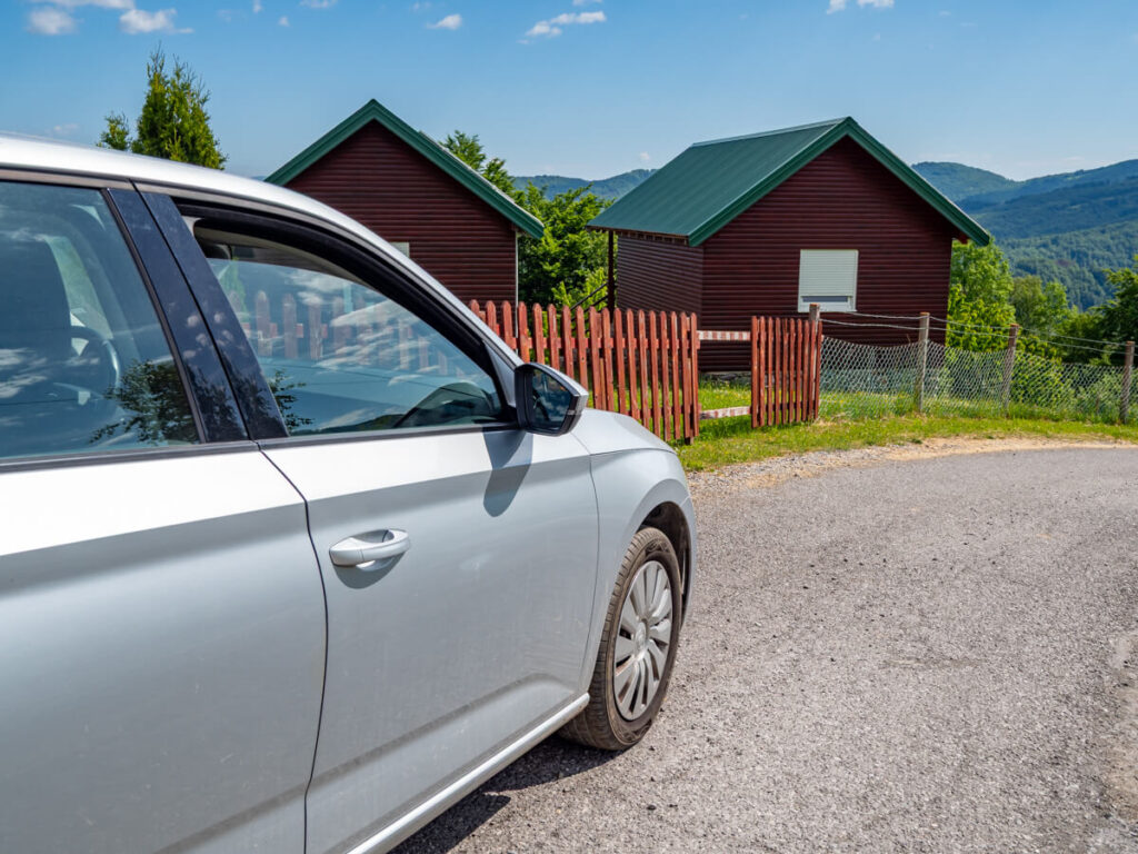 A car parked in front of a wooden cabin in rural Montenegro.
