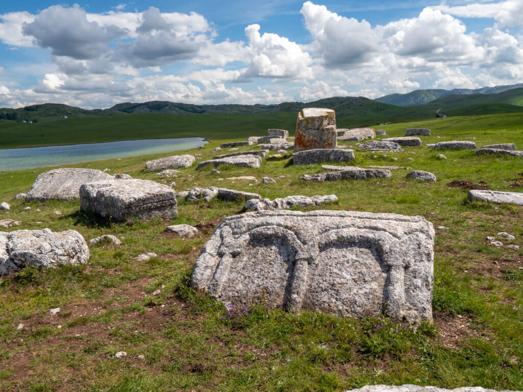 Carved medieval stećci tombstones scattered in the grass near Durmitor National Park.