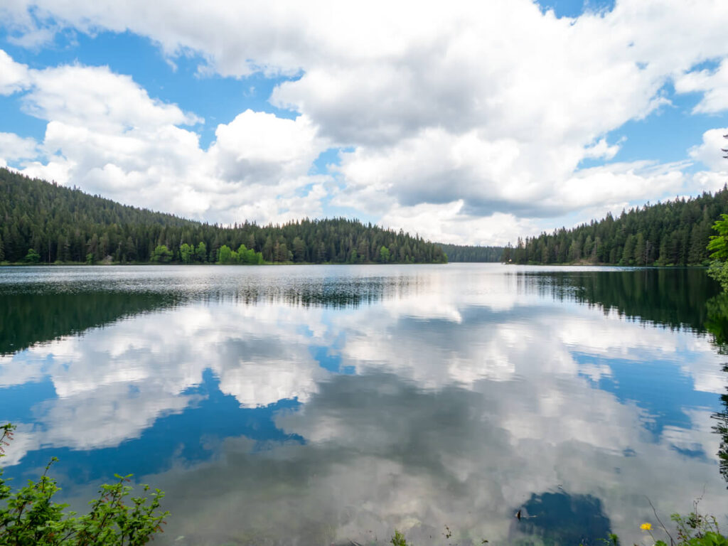 Clouds reflected in the still surface of the glacial Black Lake in Montenegro.