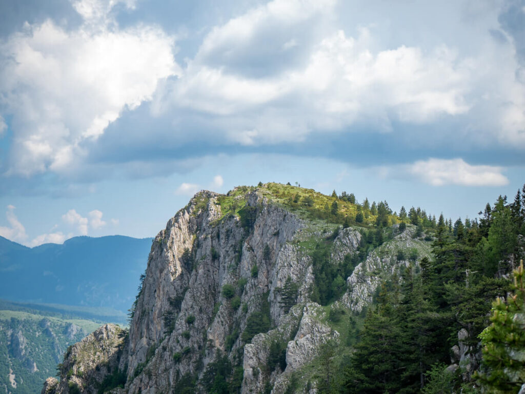 The grassy ridge of Ćurevac Peak dramatically dropping off a rocky cliff face.