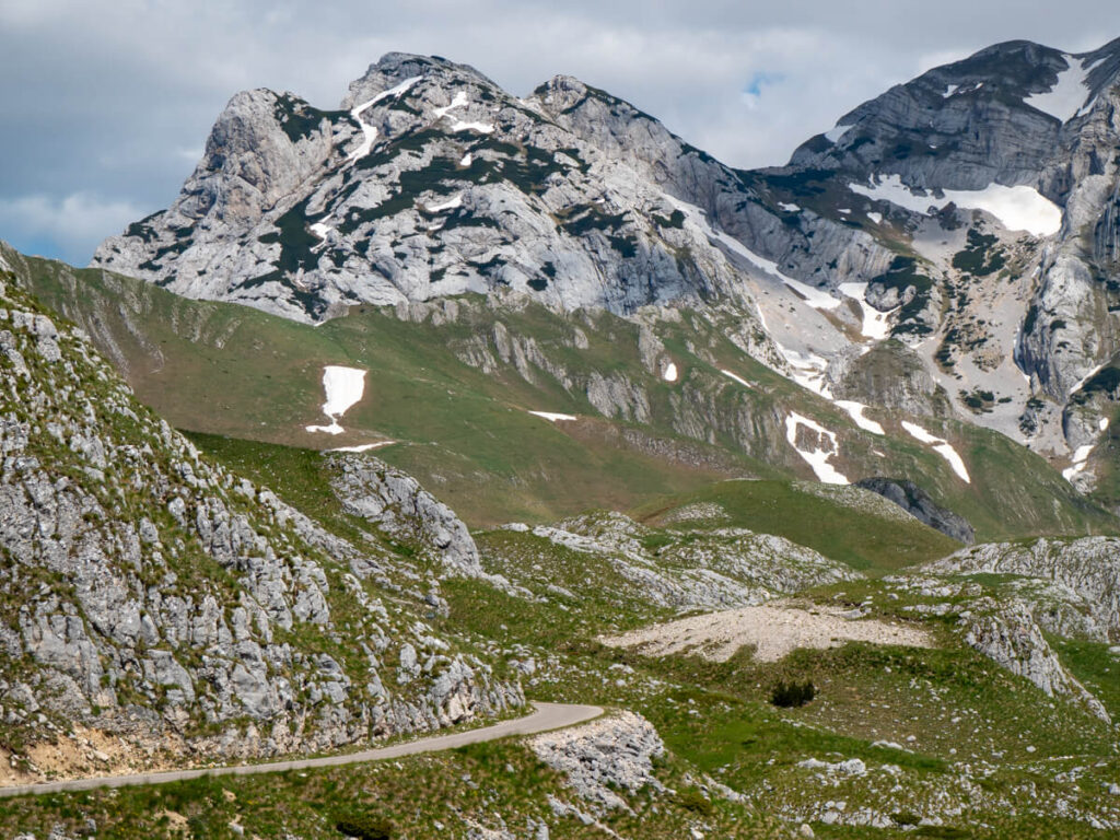 A winding road leading to dramatic grey mountains in Durmitor National Park.