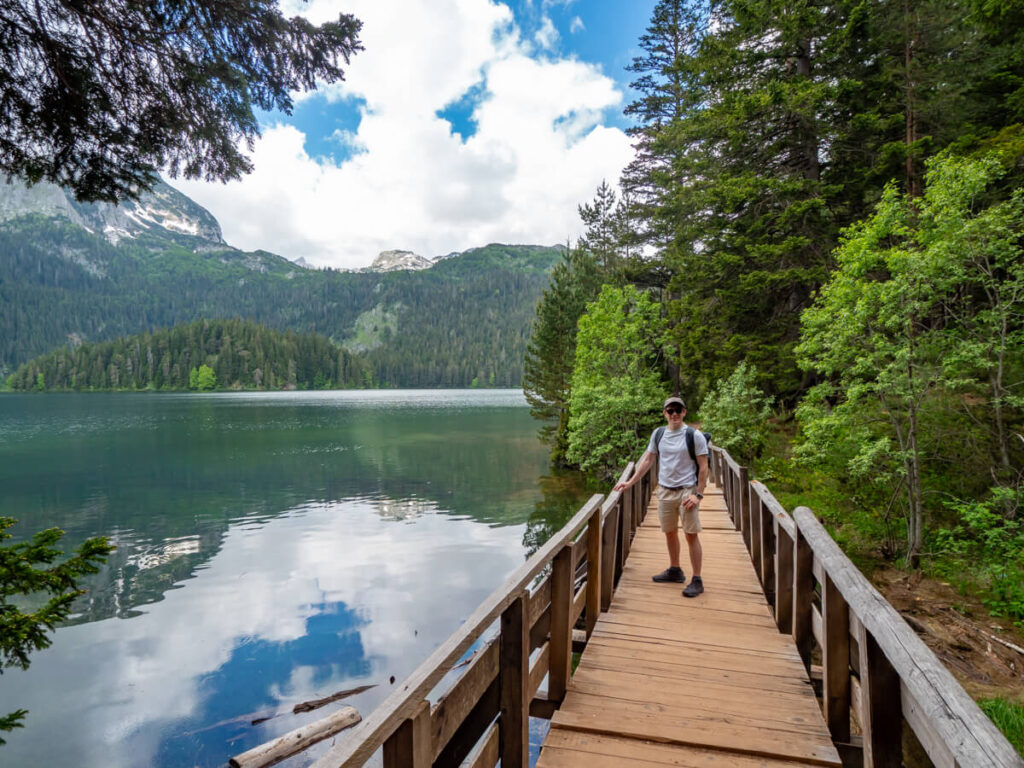 Dan standing on a wooden bridge looking at the Black Lake in Durmitor National Park.
