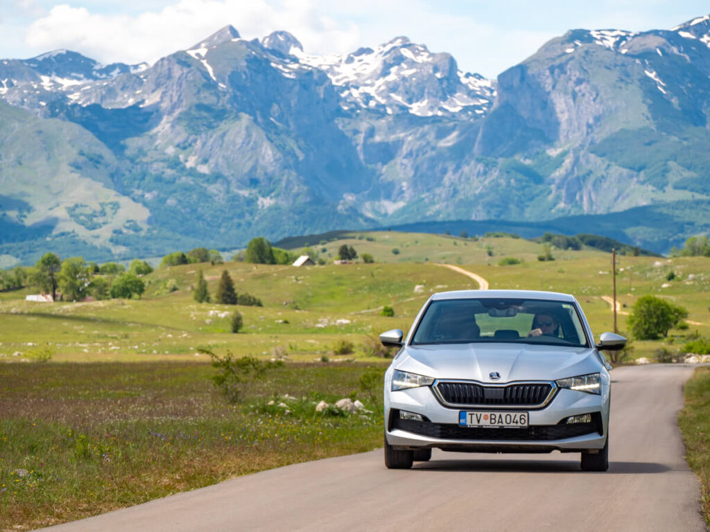 Dan driving through countryside with snowy mountains in the background.