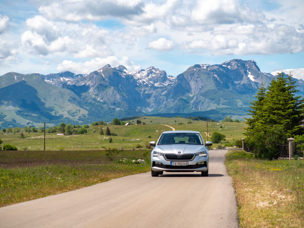 Dan driving a rental car through Durmitor National Park on a sunny day.