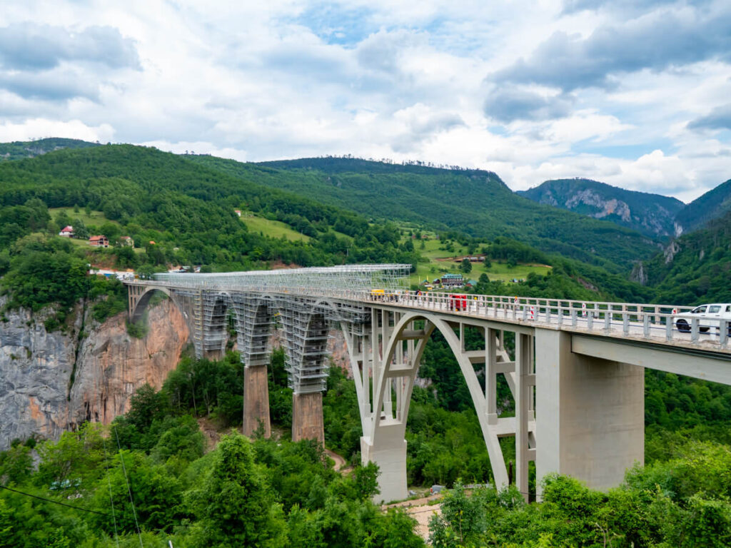 The Djurdjevica Tara Bridge stretching across a lush green gorge, covered in scaffolding.