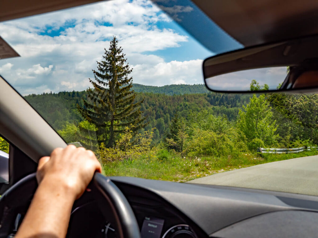 Dan driving by the lush greenery of rural Montenegro in a hire car.