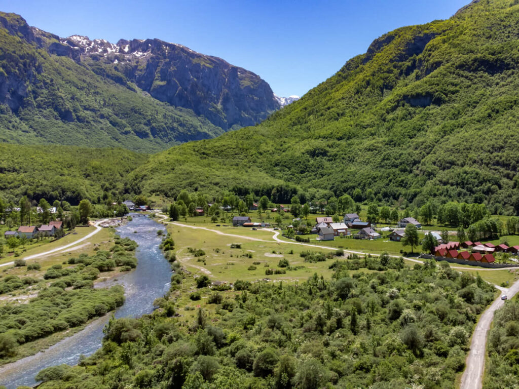 An aerial view of the Ropojana Valley with a blue river winding through lush greenery.