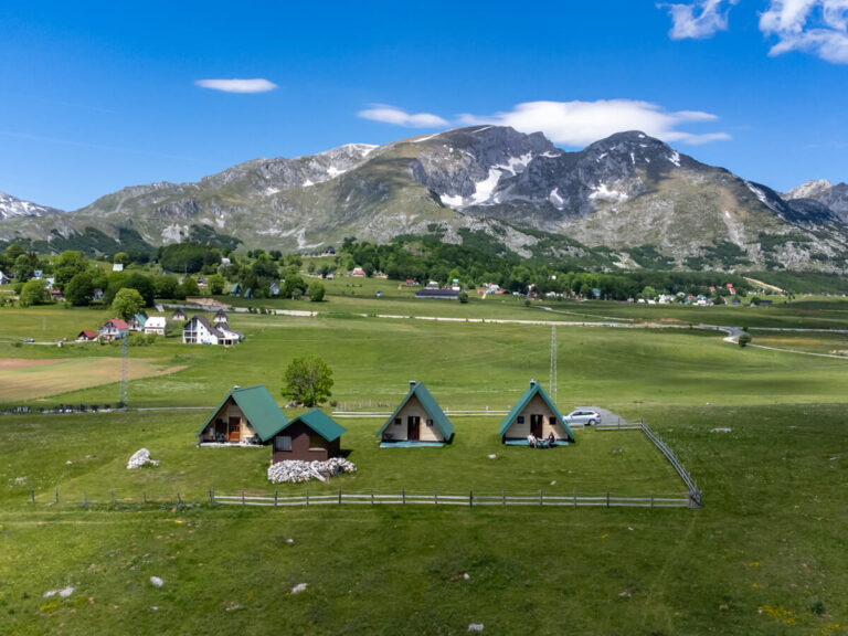 Three A-frame cabins in front of the mountains of Savin Kuk in Durmitor National Park.