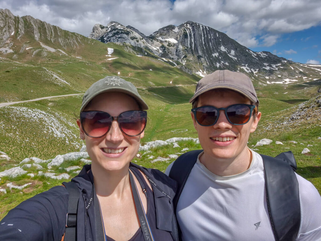Lucy and Dan smiling in front of a valley in the Durmitor Ring Road.